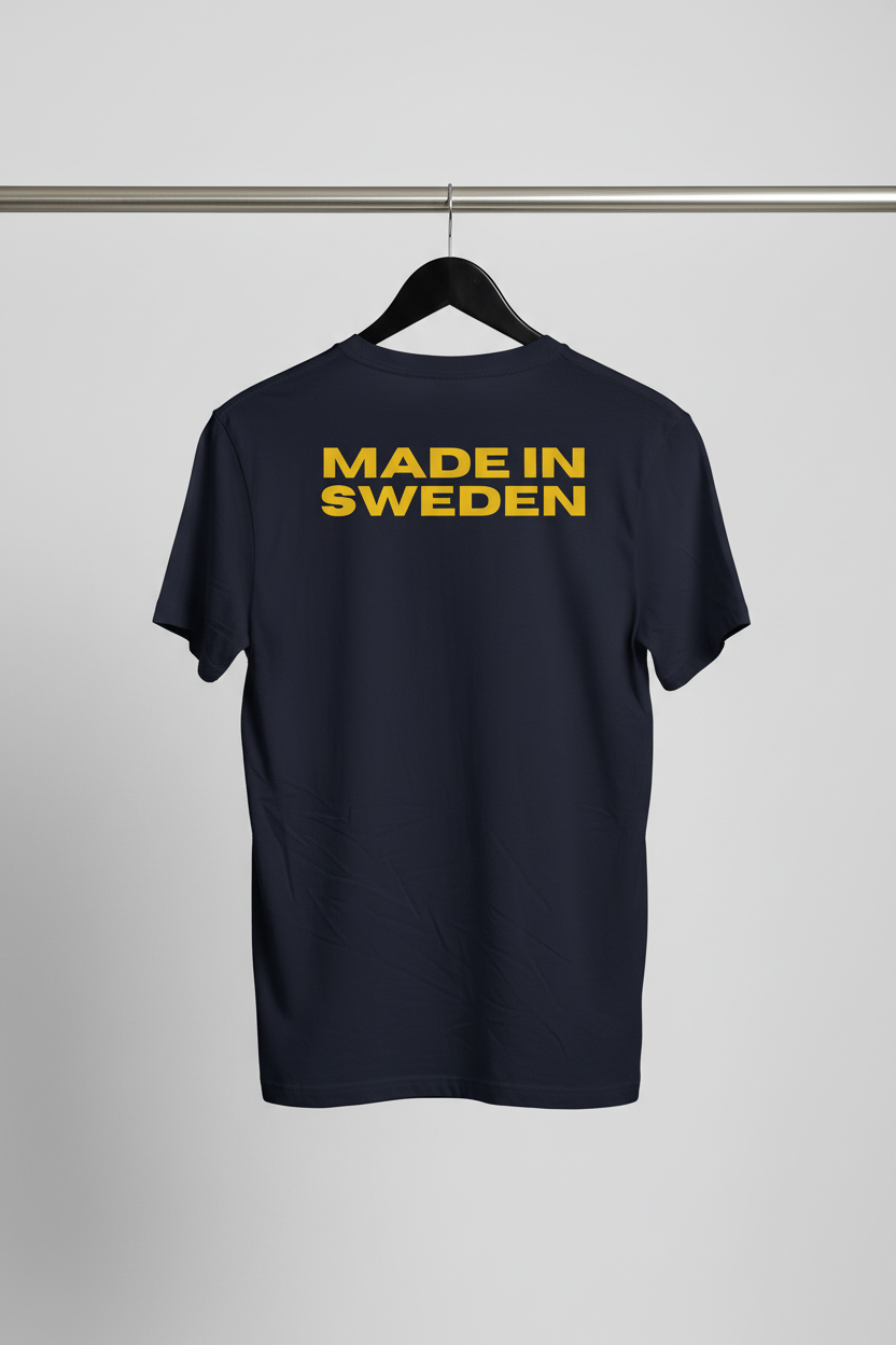 T-shirt - Made In Sweden med baksidan och motivet mot kameran på svart trägalge med ljusgrå bakgrund
